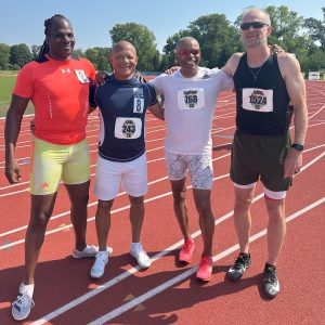 Four men smiling in front of the track after the 4x100 relay.