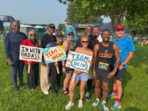 A group of athletes and supporters, some holding signs, pose together.