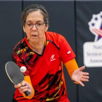 A focused table tennis player hits the ball with her paddle during a match.