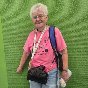 Bonita Robbins points to her name on a large green wall with the names of all of the athletes competing in the 2025 National Senior Games.