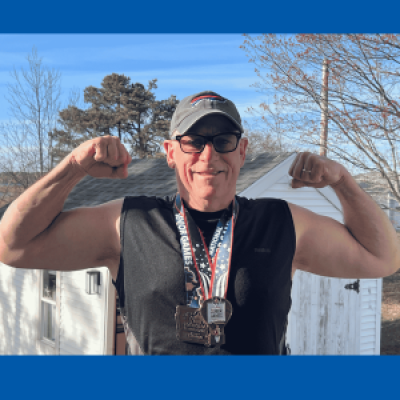 National Senior Games athlete Maximilian Cavalli flexes his muscles while wearing medals he earned at the 2019 and 2025 National Senior Games.