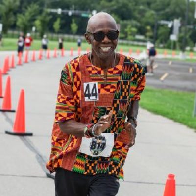 Reggie Howze power walking and smiling during a race.