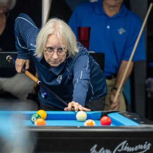 A billiards player lines up their shot on a pool table during competition at the 2025 National Senior Games.