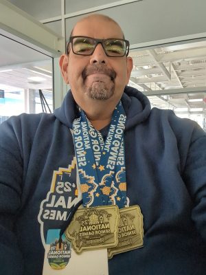 A selfie of Nicholas Delgado wearing two medals from the 2025 National Senior Games.
