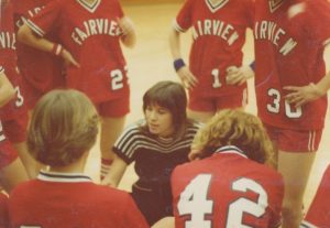 A vintage photo of Madelon Eichhorn coaching in a huddle with multiple young players surrounding her.